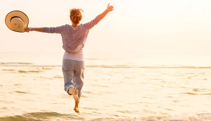 Woman running into the ocean through the sunlight.