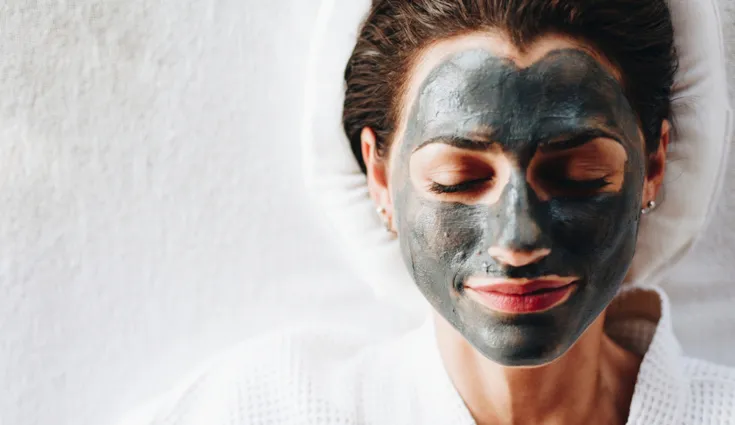 A woman wears a charcoal face mask.