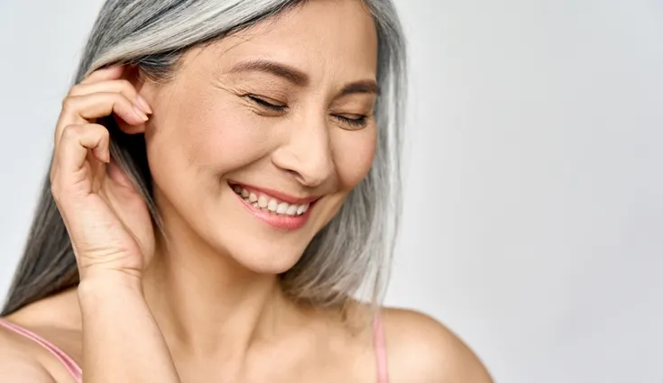 older woman smiling with glowing, clear skin.