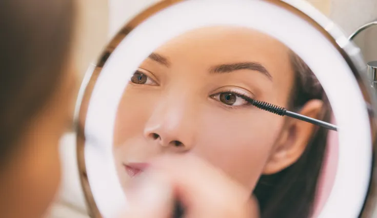 Woman applying makeup in the mirror