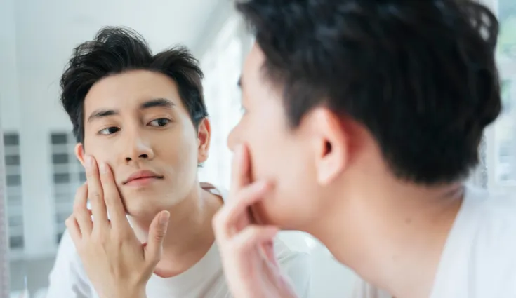 man admires clear complexion in a mirror