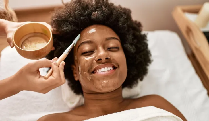 A smiling woman gets a facial.